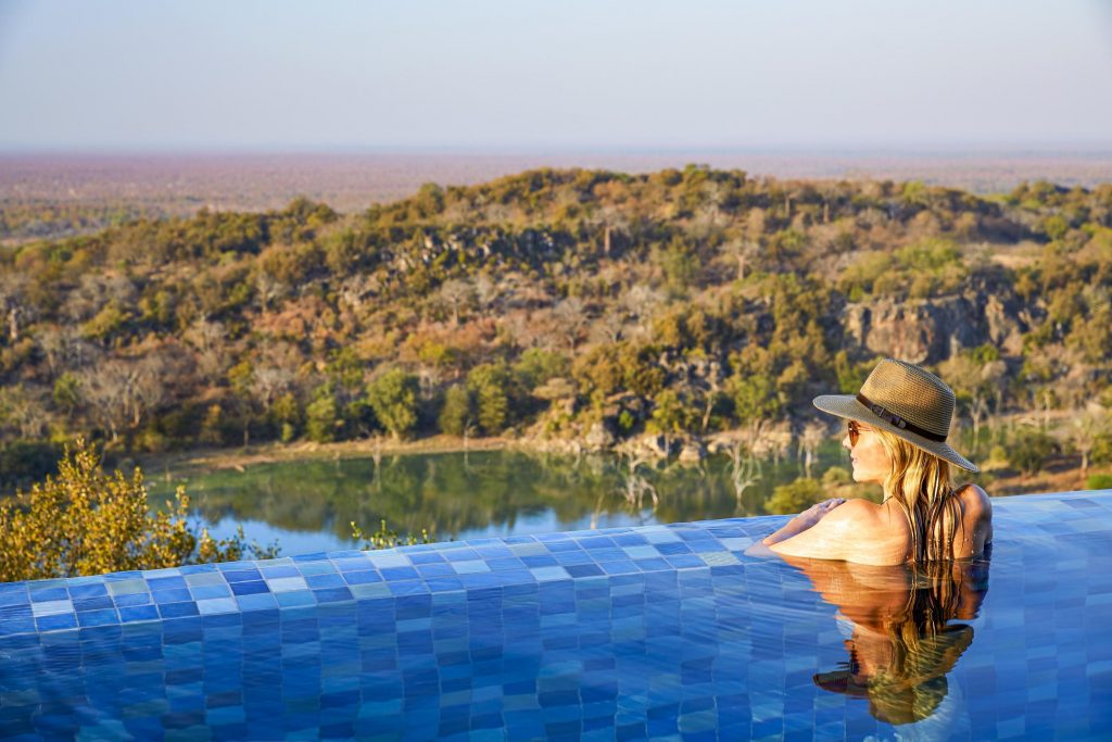 Lady in swimming pool over looking african bush