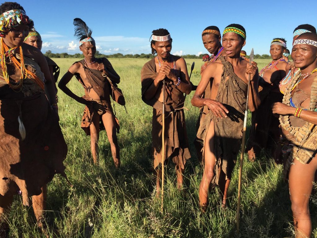 Bushmen standing in green field on Africa Safari holidays