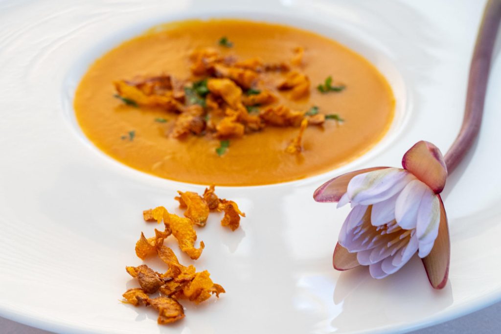 plated butternut soup with flower and grilled pumpkin skin